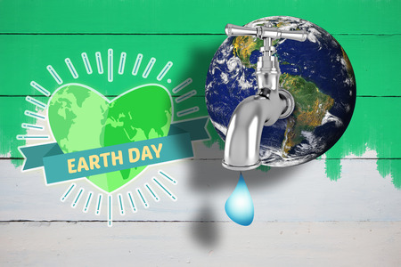 Earth with faucet against green paint on fenceの写真素材