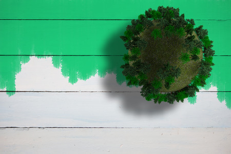Sphere covered with forest against green paint on fence
