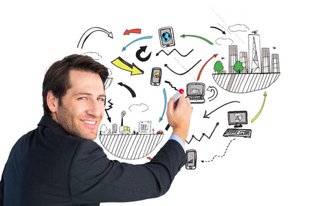 Businessman standing and writing while looking at camera against blackboardの写真素材