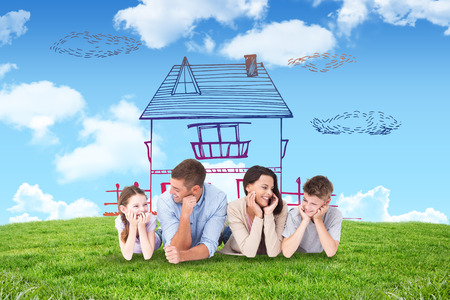 Family lying with head in hands against blue sky over green fieldの写真素材