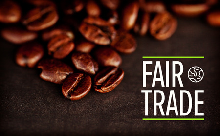 fair trade against dark blurred coffee seeds laid out together on a black tableの写真素材