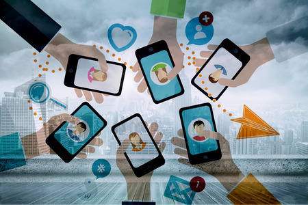 Hands holding phones against sun shining over cityの写真素材