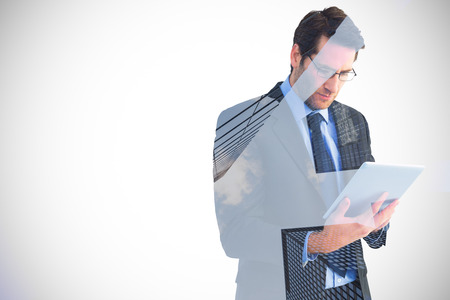 Businessman using a tablet computer against skyscraperの写真素材