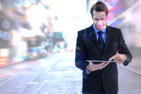 Businessman standing while using a tablet pc against blurry new york streetの写真素材