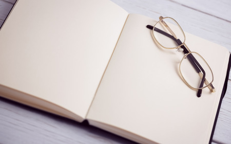 Empty notepad with reading glasses on a deskの写真素材