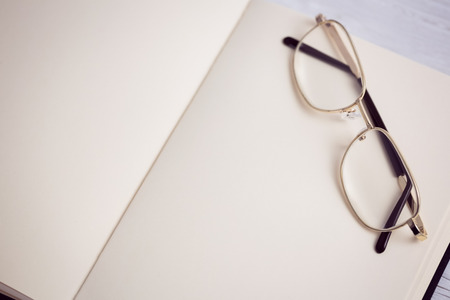 Empty notepad with reading glasses on a deskの写真素材