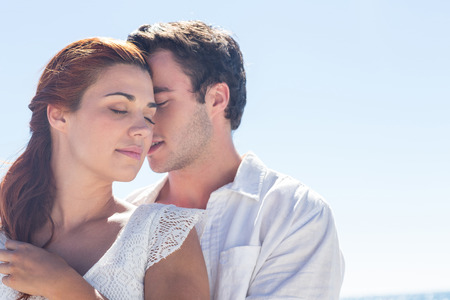 Happy couple hugging eyes closed at the beachの写真素材