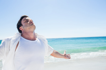 Man stretching his arms in front of the sea at the beachの写真素材