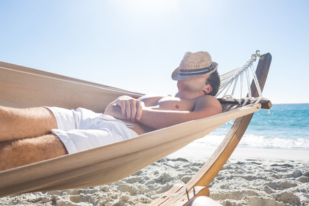 Handsome man resting in the hammock at the beachの写真素材