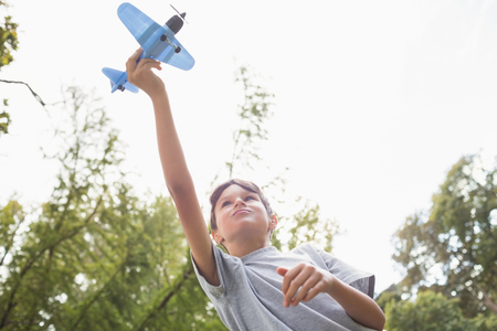Boy playing with a toy plane at park on a sunny dayの写真素材