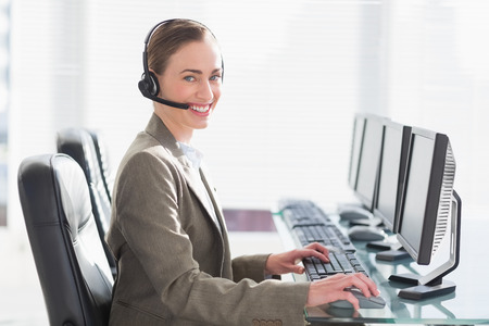 Smiling businesswoman with headset using computers in office