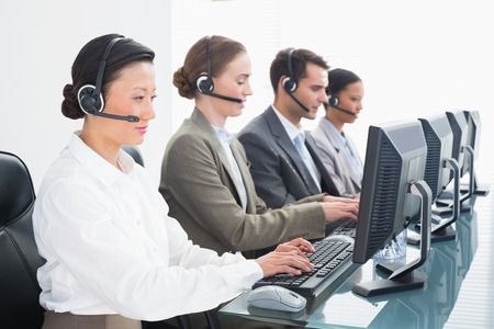 Business people with headsets using computers in officeの写真素材