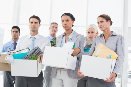 Unhappy fired business people holding box in office