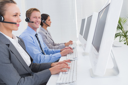 Business team working on computers and wearing headsets in call centerの写真素材