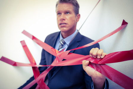 Businessman trapped by red tape on white backgroundの写真素材