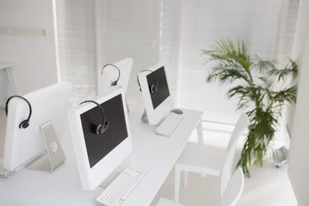 Computers and headsets in empty officeの写真素材