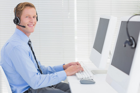 Handsome agent with headset typing on keyboard in call center