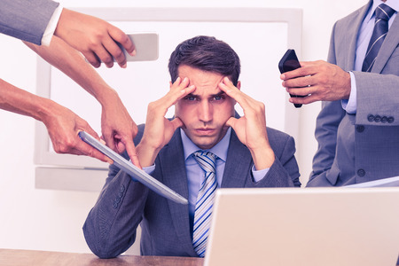 Worried businessman with head in hands sitting at the officeの写真素材