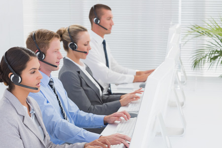 Business team working on computers and wearing headsets in call centerの写真素材