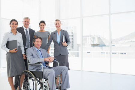 Disabled businessman with his colleagues smiling at camera in the officeの写真素材