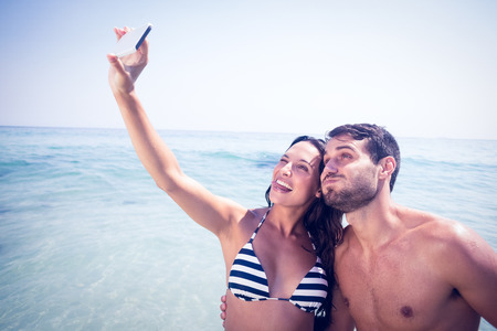Happy couple taking a selfie at the beachの写真素材