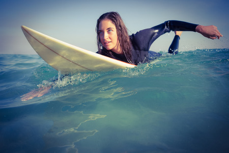 woman in wetsuit surfing on sunny day