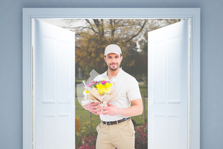 Delivery man holding bouquet  against flowers in a parkの写真素材