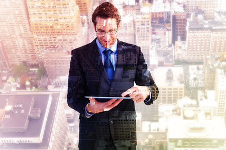 Businessman standing while using a tablet pc against new yorkの写真素材