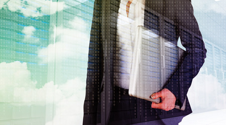 Businesswoman holding laptop against server hallwayの写真素材