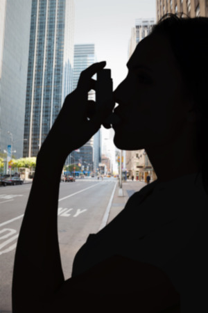 Asthmatic brunette using her inhaler  against new york streetの写真素材