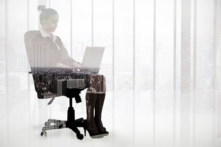 Businesswoman sitting on swivel chair with laptop against high angle view of city skylineの写真素材