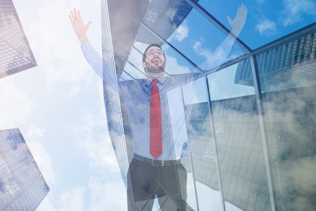 Happy cheering businessman raising his arms against skyscraperの写真素材