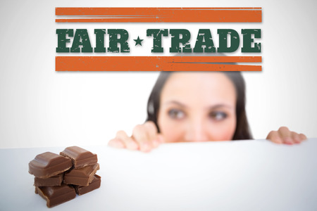 Pretty brunette peeking at chocolate against white background with vignetteの写真素材