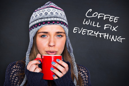 Beautiful woman in warm clothing drinking coffee against black background