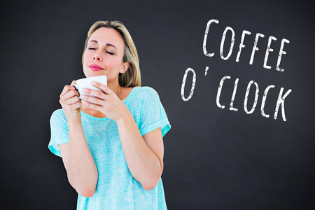 Peaceful blonde with hot beverage relaxing against black background