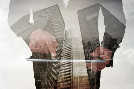 Businessman using his tablet pc  against low angle view of skyscrapersの写真素材