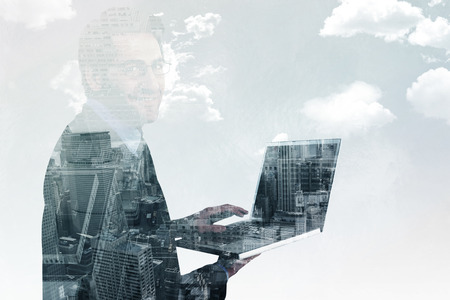 Smiling businessman using a laptop  against new york skyline