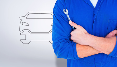 Male mechanic holding spanner on white background against grey vignetteの写真素材