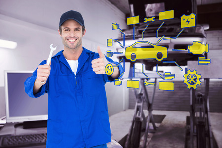 Happy mechanic holding spanner against auto repair shopの写真素材