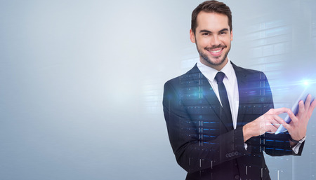 Businessman using his tablet while looking at the camera  against grey vignetteの写真素材