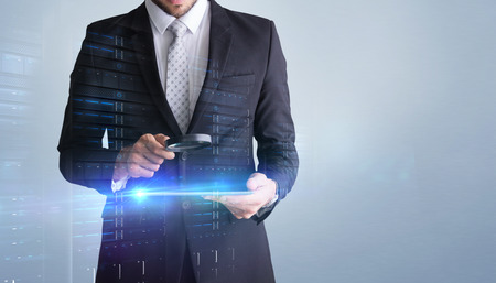 Concentrated businessman using magnifying glass against grey vignetteの写真素材