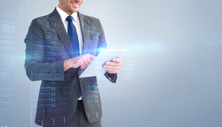 Businessman using his tablet pc  against grey vignetteの写真素材