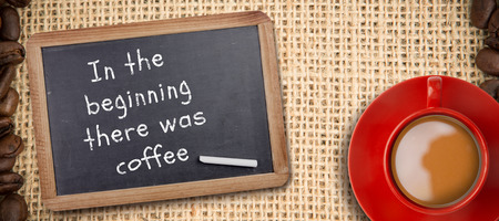 Red cup of coffee against chalkboard with piece of chalkの写真素材