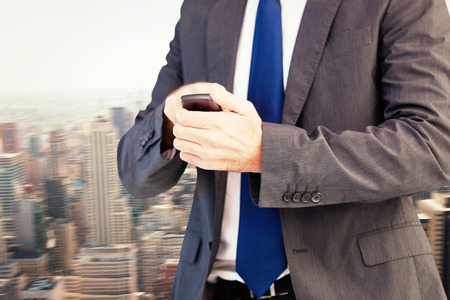 Focused businessman texting on his mobile phone against new yorkの写真素材