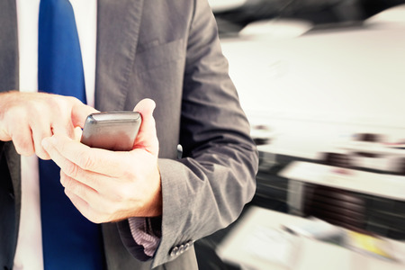 Businessman sending a text message against classroomの写真素材