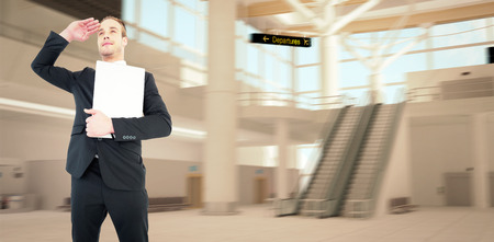 Smiling businessman looking and holding laptop against airport terminalの写真素材
