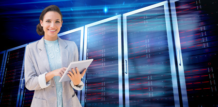 Brunette using tablet pc against composite image of server towers