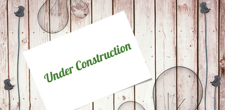 The word under construction and white card against wooden background with plugs