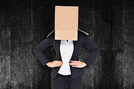 Businesswoman with box over head against black backgroundの写真素材