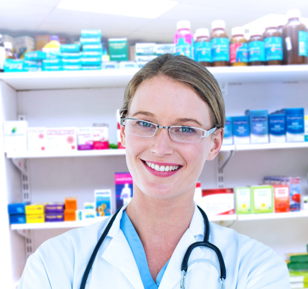 Smiling doctor looking at camera against close up of shelves of drugsの写真素材